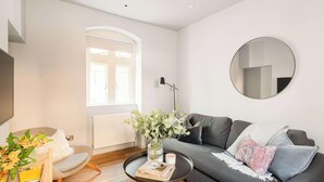 A modern living room with a grey sofa, a round mirror, a floor lamp, and a vase with flowers. - Split-Level Deluxe Suite · Sleeps 4 in Bath (Bath and North East Somerset)