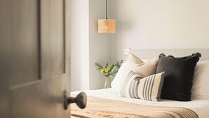 A bedroom with a bed, pillows, a bedside table with a vase of flowers, and a hanging light fixture. - King Suite for 4 · Courtyard Views in Bath (Bath and North East Somerset)