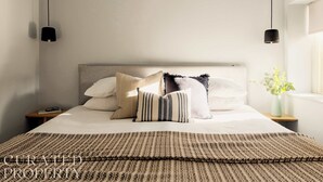 A neatly made bed with a patterned bedspread, multiple pillows, and bedside tables with lamps.