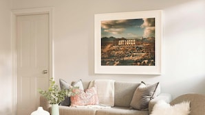 A living room with a framed picture of a desert landscape and the word "ANTIQUE" on it. - Elegant King Suite · Behind Thermae Spa (Bath and North East Somerset)