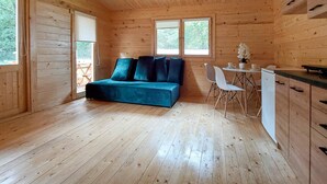 L’intérieur chaleureux d’un chalet comprend un lit, une petite table à manger, des chaises et un coin cuisine.