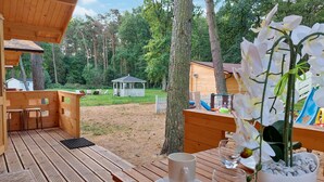 Une terrasse en bois avec une table et des chaises, un kiosque en arrière-plan et un toboggan.