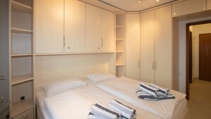 Quarto de hotel com uma cama grande, duas mesas de cabeceira, um guarda-roupa e um banheiro.