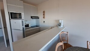 A compact kitchen with a microwave, oven, and coffee maker on a white countertop.