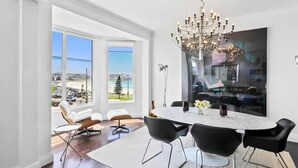 A modern dining area with a large window, a chandelier, and a view of the cityscape.