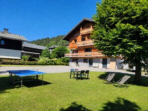 Een hotel met een houten gevel, een terras en een tennisbaan.