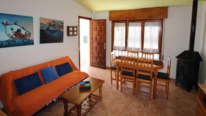 A cozy living room with a wooden sofa, a dining table with chairs, a fireplace, and artwork on the walls. - Cozy Beach Home: Free WiFi, Optional AC, Pet-Friendly, Dog Beach Nearby (Deltebre)