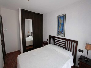 A bedroom with a bed, a nightstand, a lamp, a mirror, and a framed picture on the wall. - Charming Dog-Friendly Home w/ Private Pool, Near Beach, Free WiFi, A/C Option (Deltebre)