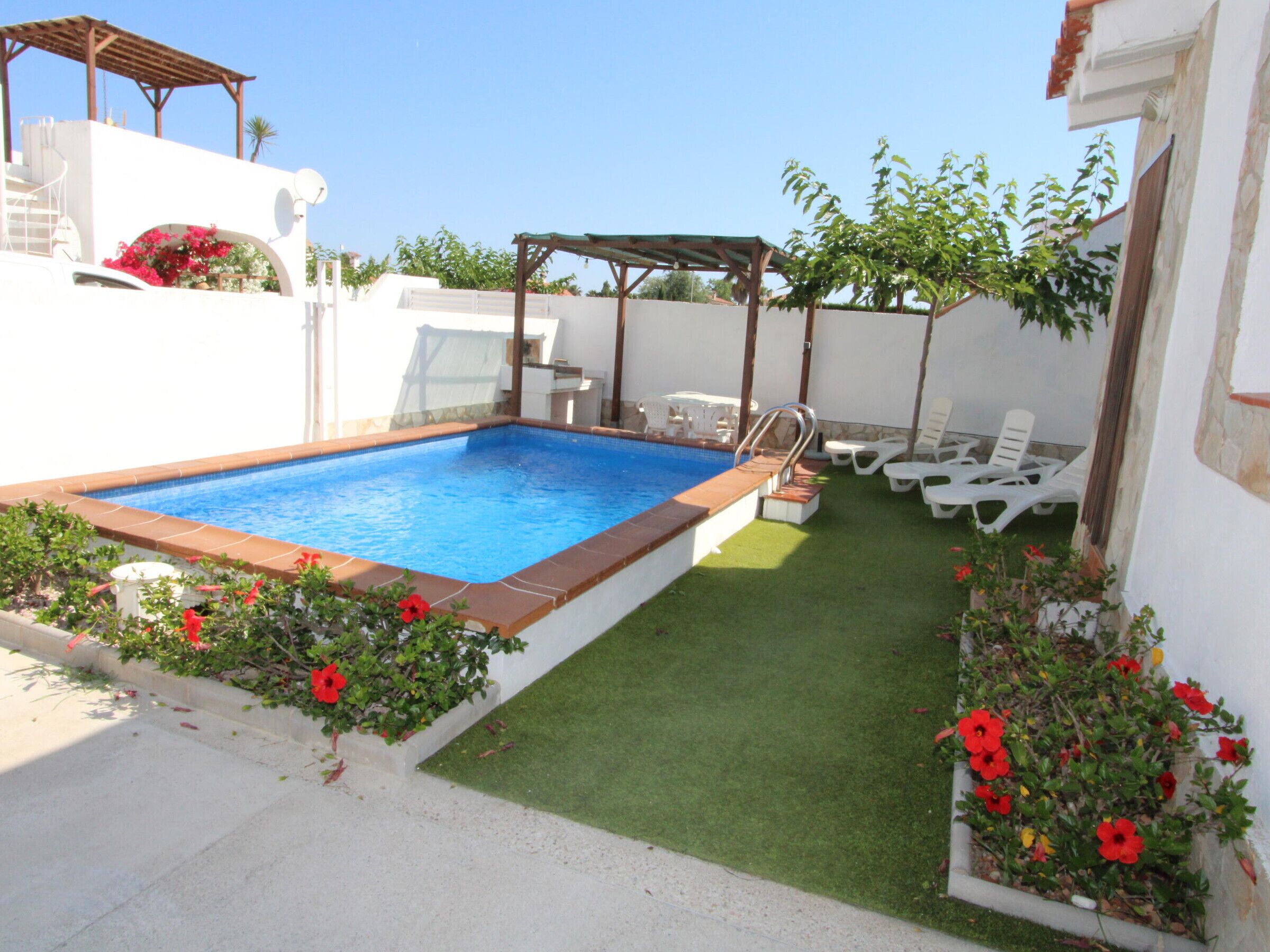 A swimming pool with a wooden deck, a covered seating area, and a grassy lawn with sun loungers.