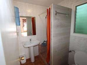 A bathroom with a white sink, a shower with a glass door, and a toilet.