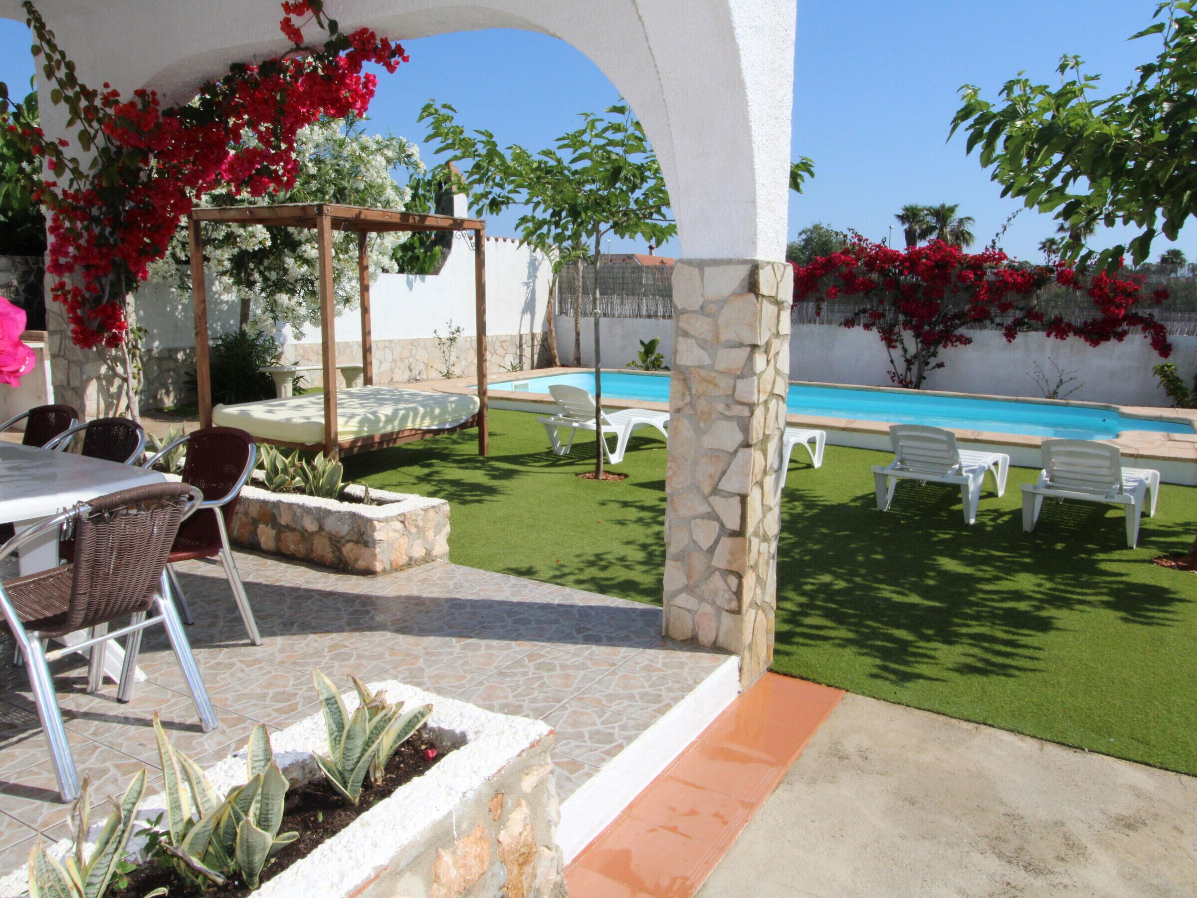 Un espace patio avec une piscine, du mobilier d’extérieur et une pergola ornée de plantes à fleurs.