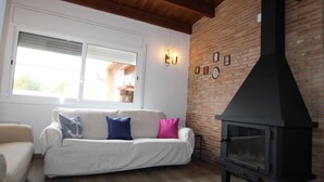 A living room with a sofa, a fireplace, and a window. - Beachside Family Home: Private Pool, Free Wi-Fi, Pets Welcome, Near Dog-Friendly Beach (Deltebre)