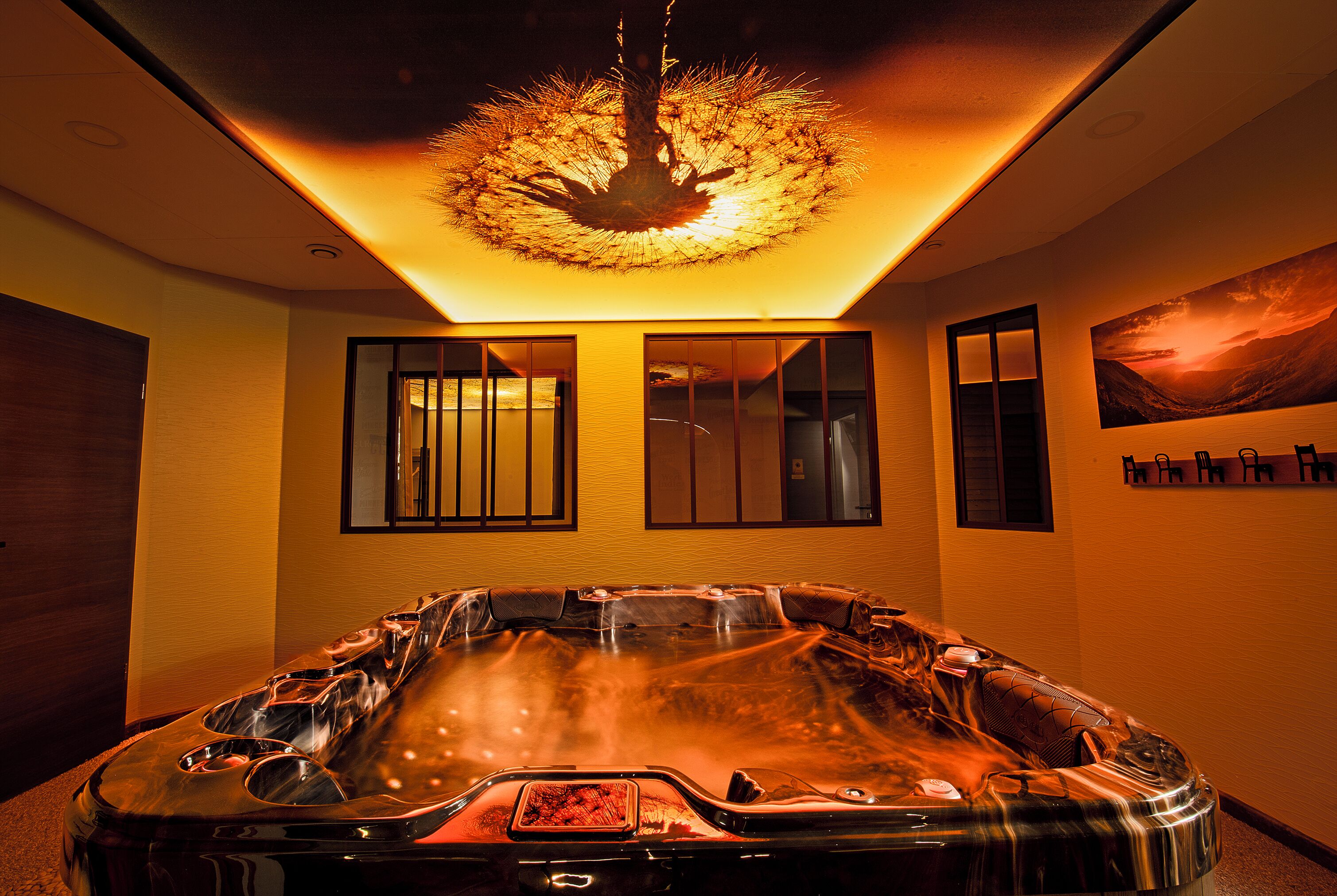 A spa room with a hot tub, wooden flooring, and a ceiling light fixture.