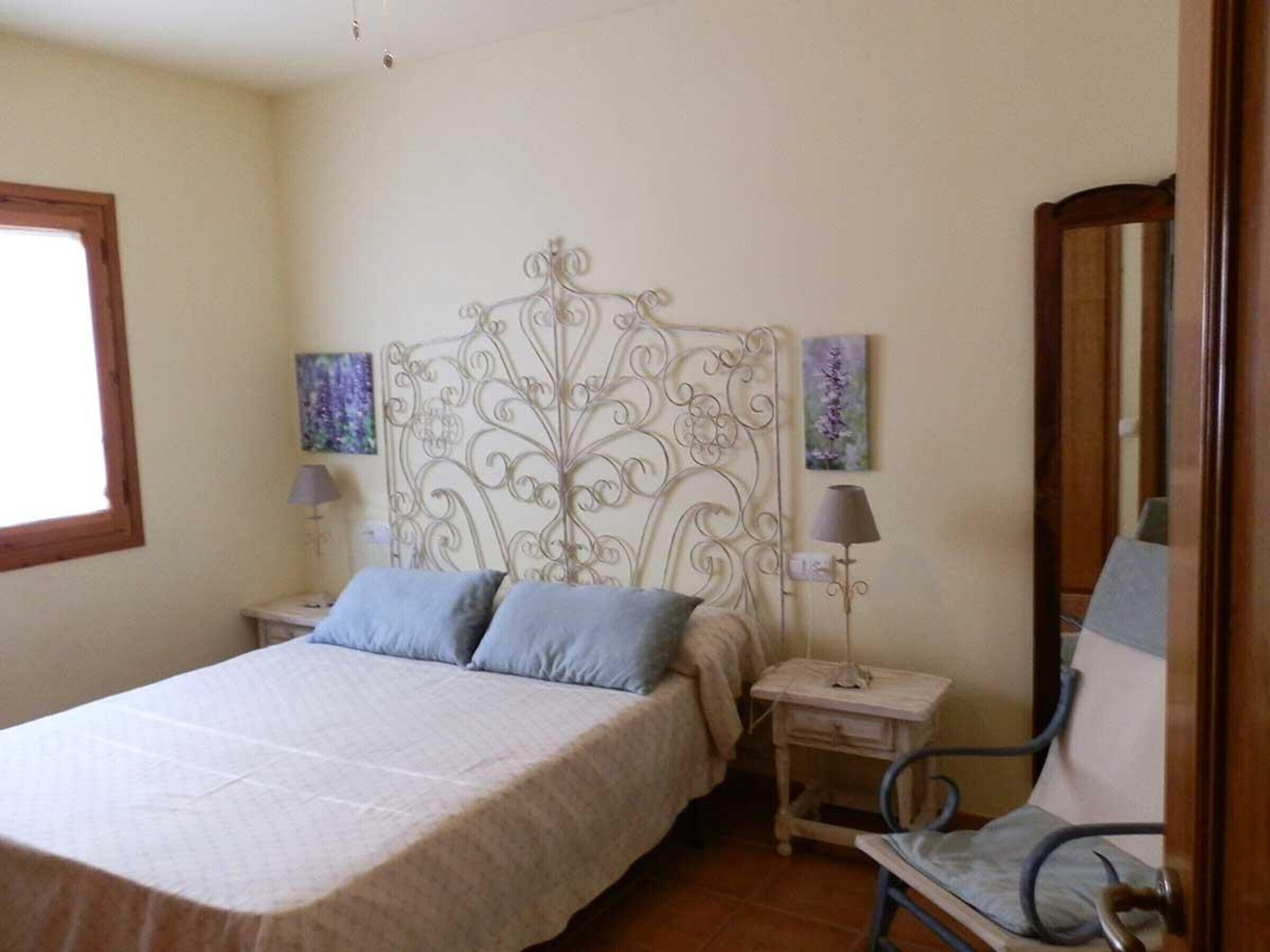 Une chambre à coucher comprenant un lit, deux tables de chevet, une chaise et une tête de lit décorative.