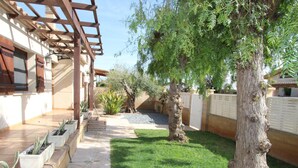Une cour intérieure agrémentée d’une pergola, de plantes en pot, d’un arbre et d’un chemin dallé.
