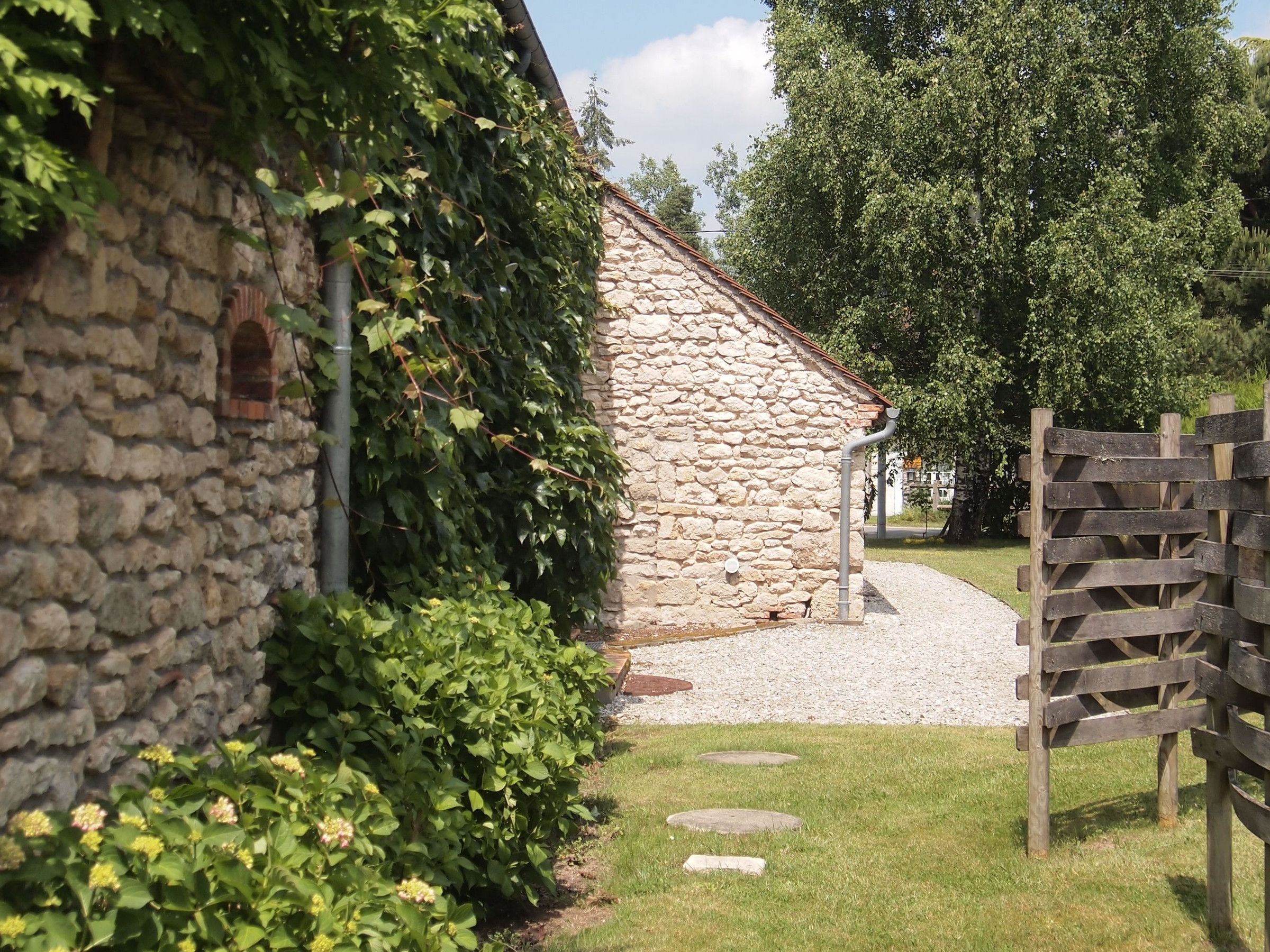 A stone building with a gravel path leading to a wooden gate.