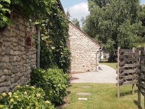 A stone building with a gravel path leading to a wooden gate.