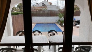 A view through a window of a room with a pool table, chairs, and a view of a swimming pool outside. - Cozy Beachside Home: Private Pool, Pet-Friendly, WiFi, A/C Option, Near Dog Beach (Deltebre)