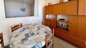 Ein Essbereich mit einem runden Tisch, Stühlen, einem Holzschrank und einem Fenster mit Vorhängen.