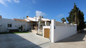 Ein modernes Haus mit Terrasse, einer Holztür und einer weißen Wand.