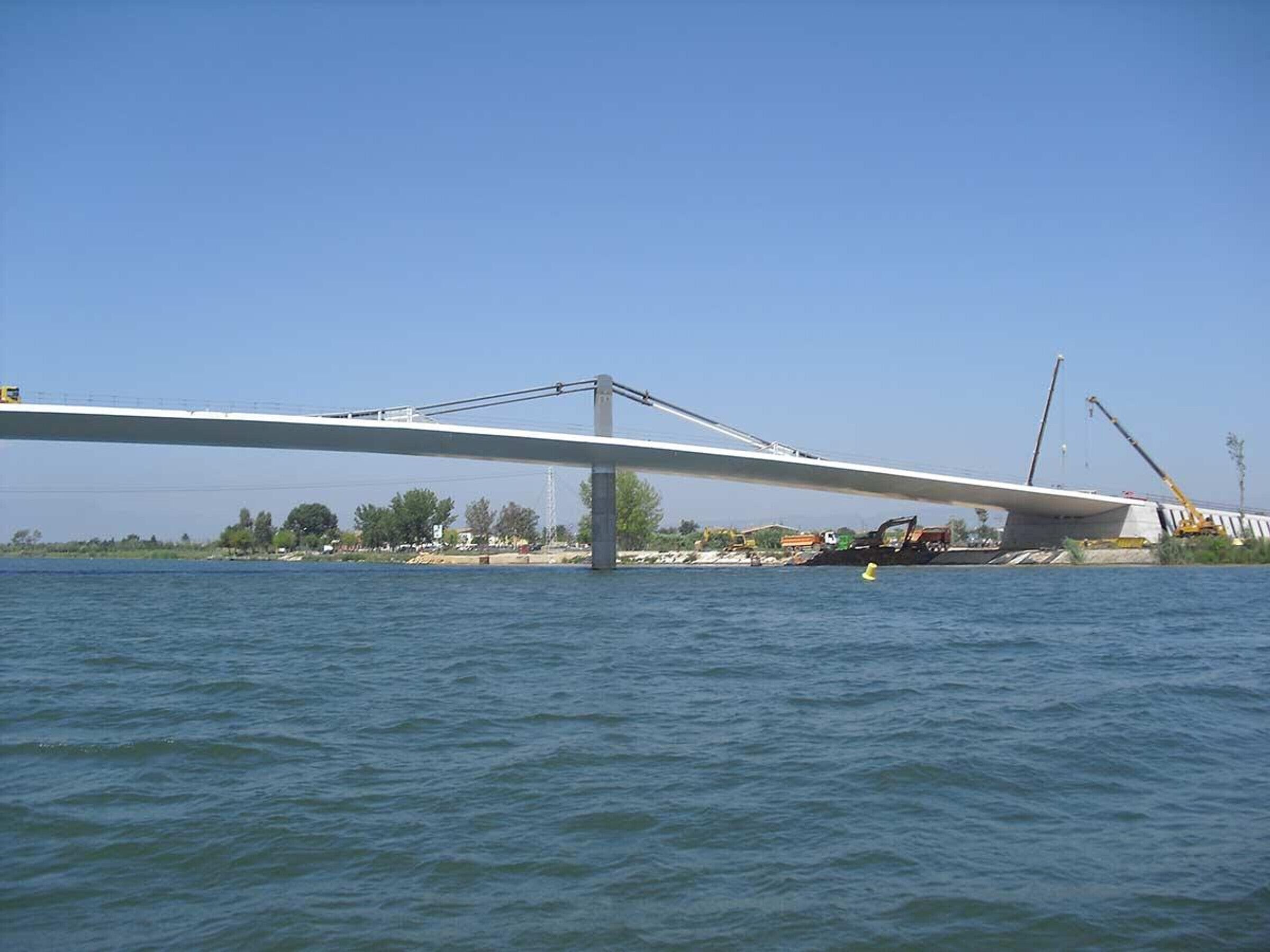 A bridge over water with construction equipment and a crane.