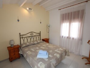 A bedroom with a bed, nightstands, a lamp, and a window with curtains.
