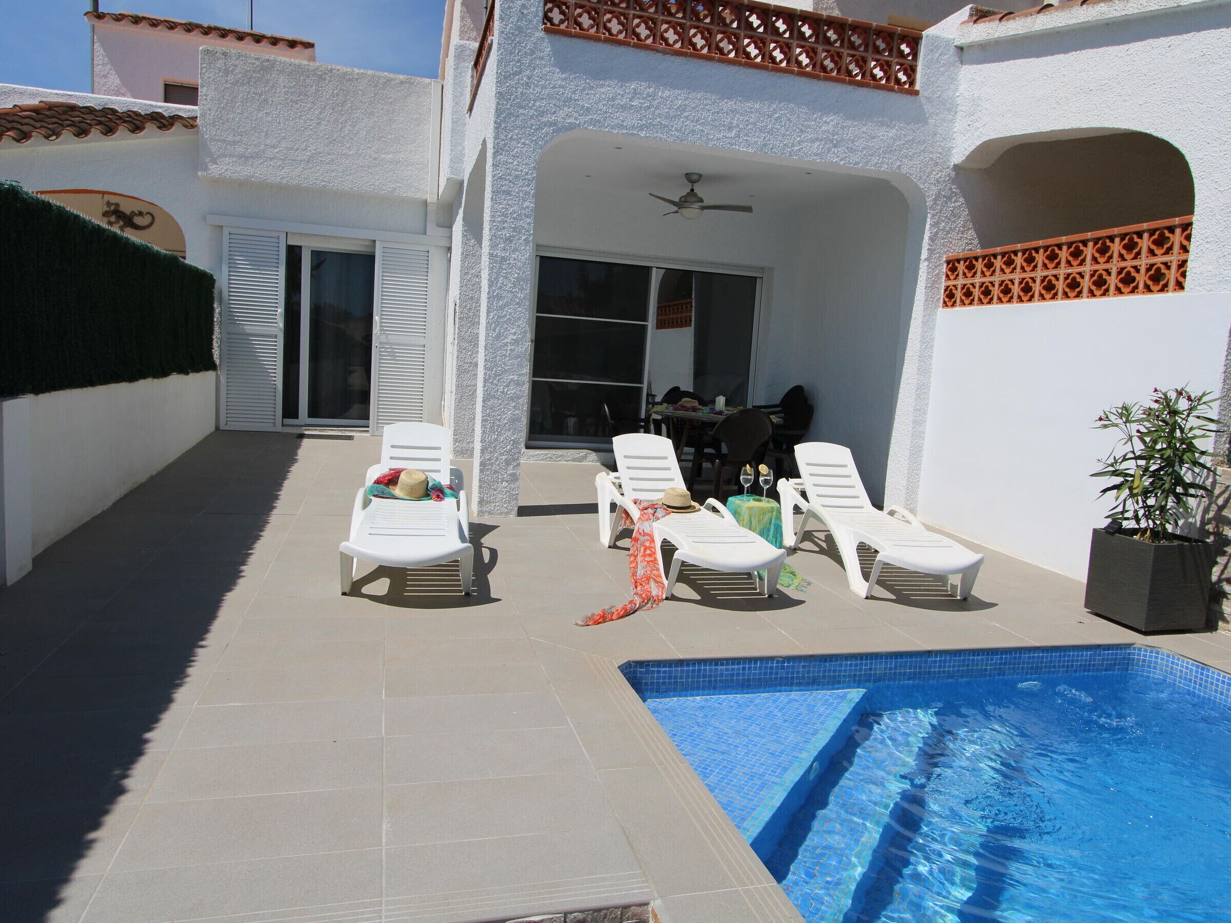 A poolside area with lounge chairs, a small table, and a potted plant.