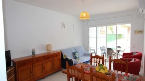 Et spiseområde med et træbord, stole, en sofa og en loftlampe.