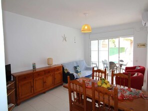 A dining area with a wooden table, chairs, a sofa, and a ceiling light.