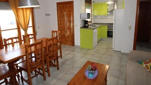 Un comedor con mesa y sillas de madera, una cocina con armarios verdes y una sala de estar con sofá.