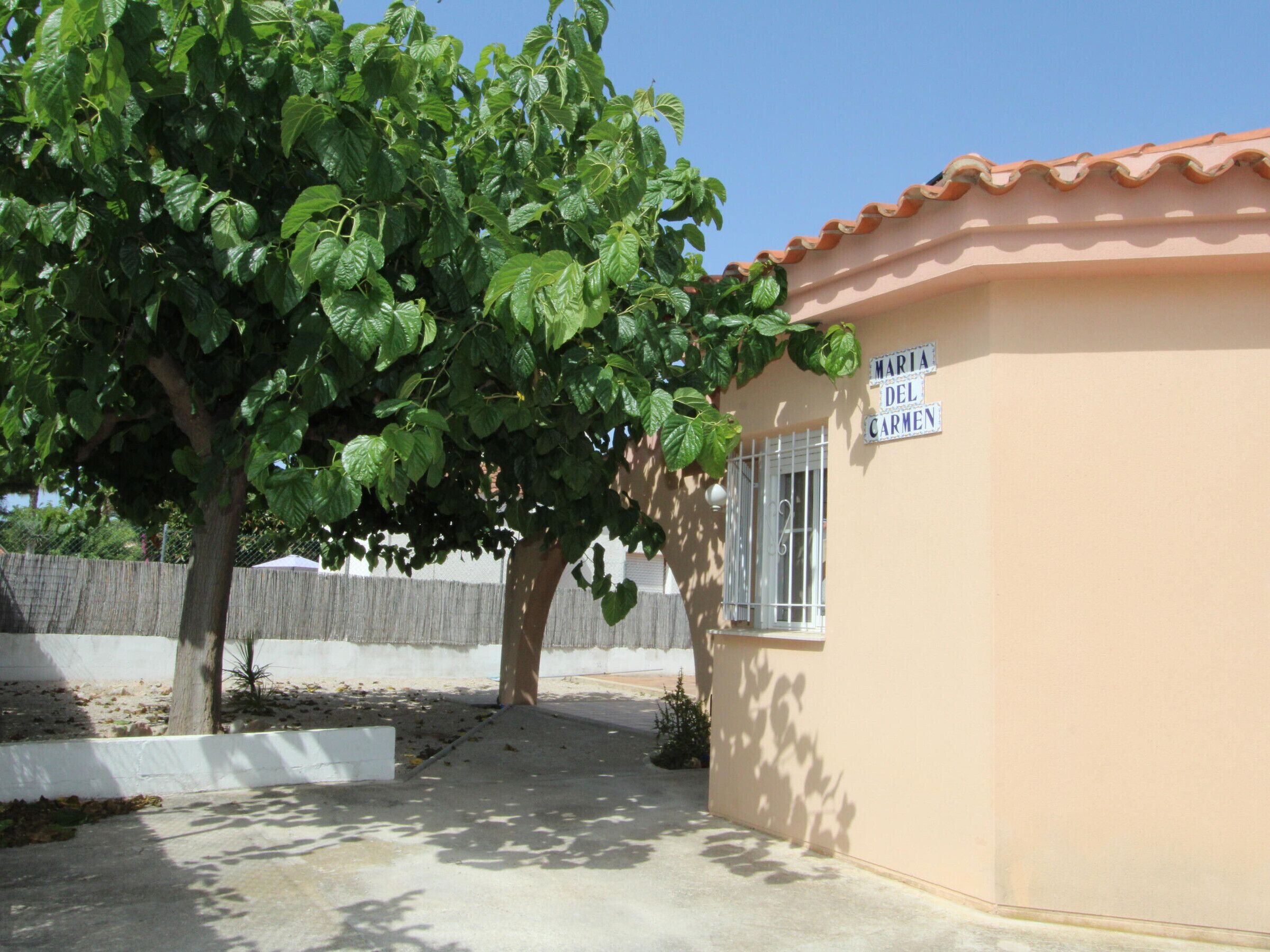 A building with a sign reading 'MARIA DEL CARMEN' and a tree in front.