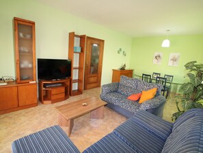 A living room with a television, sofa, coffee table, and a dining area with chairs and a table. - Beachside Oasis: Private Pool, Pet Friendly, Free WiFi, Optional A/C, Dog Beach Nearby! (Deltebre)