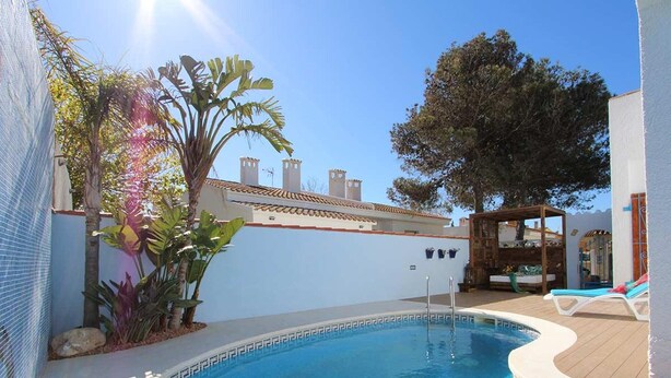 A swimming pool with a wooden deck, surrounded by plants and a pergola. - Beachside Getaway: Private Pool, Free WiFi, Pet Friendly, Air Con, Near Dog Beach (Deltebre)