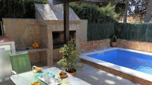 A patio with a pool, a table with bowls of fruit, a grill, and a potted plant. - Perfect Vacation Home: Private Pool, Near the Sea, Free WiFi, Pet-Friendly, Dog Beach. (Deltebre)