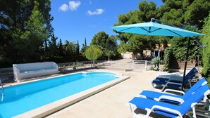 Ein Swimmingpool mit blauem Wasser, umgeben von Liegestühlen und einem Sonnenschirm.