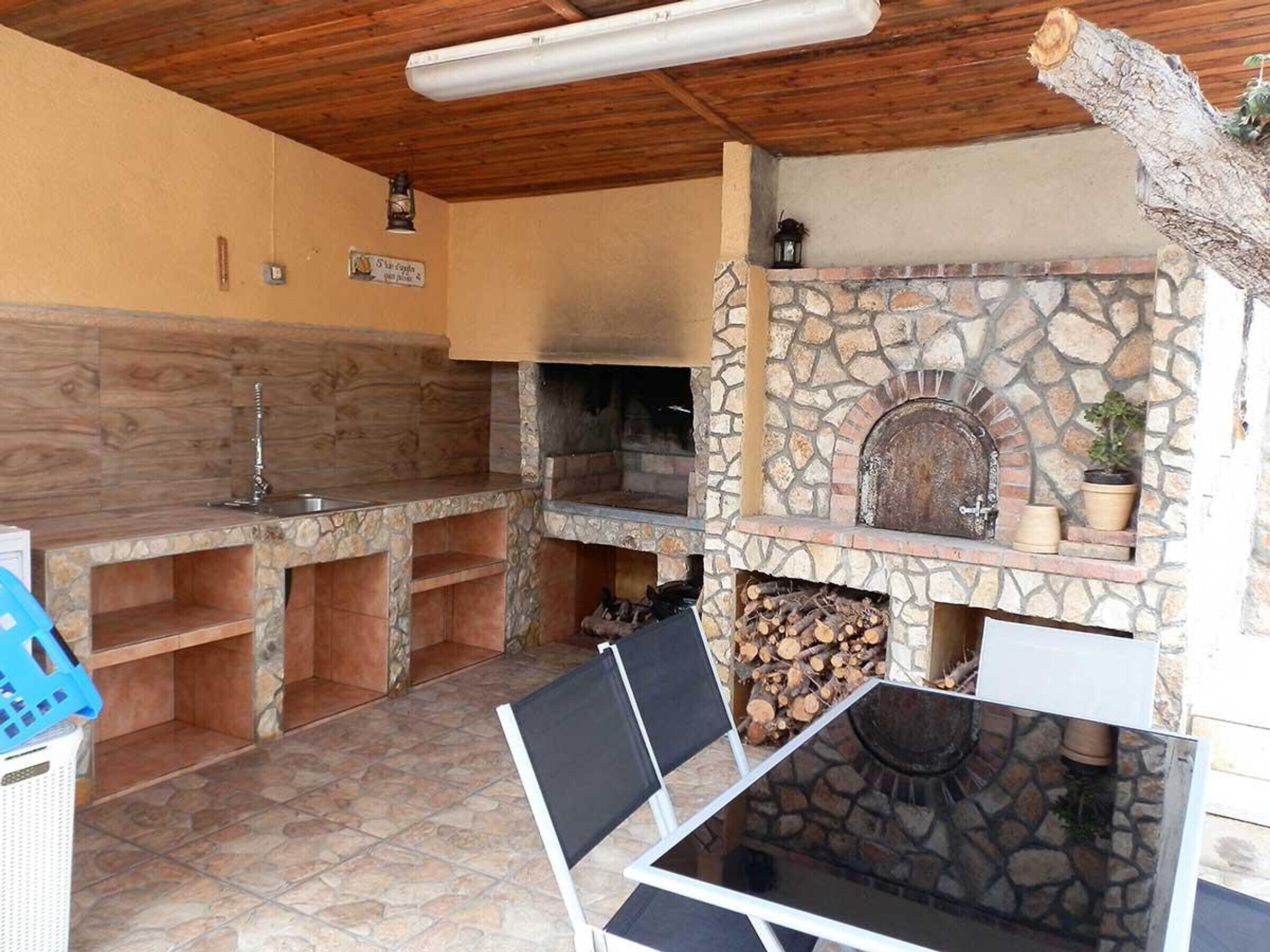 A stone fireplace with a rustic design, a wooden ceiling, and a tiled floor.