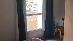 Habitació amb finestra, una cadira i un radiador.