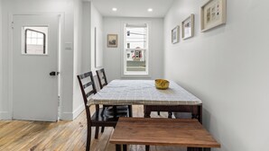 Een eethoek met een houten tafel, stoelen en een geruit tafelkleed.