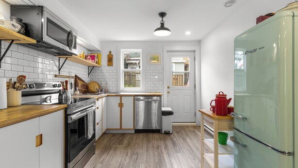 Een moderne keuken met witte kasten, roestvrijstalen apparatuur en een groene koelkast.