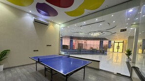 A ping pong table in a modern room with a glass wall, wooden flooring, and a ceiling with colorful geometric shapes. - VIP resort chalet - 18 (Riyadh)