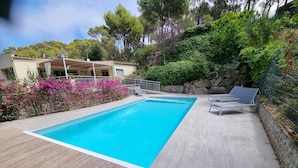 A rectangular swimming pool with a wooden deck and a stone wall. - Maison Contemporaine Avec Piscine à Mi-chemin Entre la Plage de Sa Tuna et Begur (Begur)