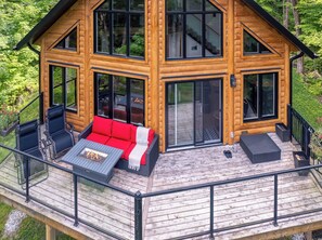 A log cabin with a deck, outdoor seating, and a fire pit. - Breathtaking view of Mont Tremblant: a daily spectacle to savor (Mont Tremblant)