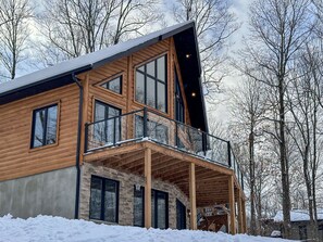 En moderne hytte med balkon og store vinduer.