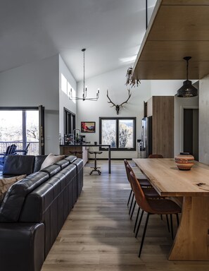 Relax in this open-plan living space with a large dining table and comfortable sofa, featuring a unique deer skull and contemporary decor.