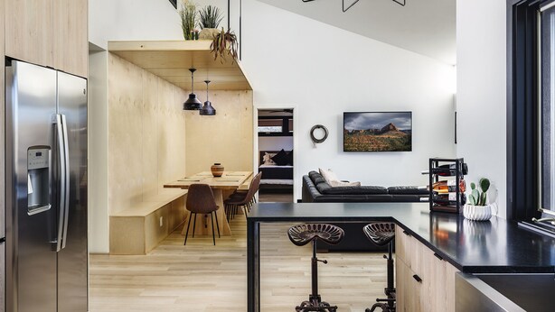 A modern kitchen with a central island, wooden cabinets, and a stainless steel refrigerator.