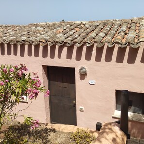 Un bâtiment avec un toit recouvert de tuiles, une porte et une petite fenêtre.