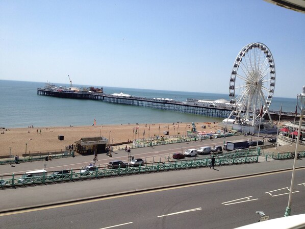 A beach with a pier, a Ferris wheel, and a road with vehicles.