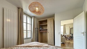 A bedroom with a large bed, a wardrobe, a radiator, and a window with curtains.