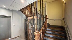 A staircase with a wooden handrail and metal railings, leading to an upper floor.
