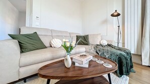 A modern living room with a beige sofa, a wooden coffee table, and a floor lamp.